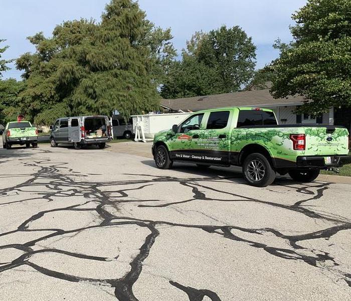 a green SERVPRO truck parked in a residential neighborhood