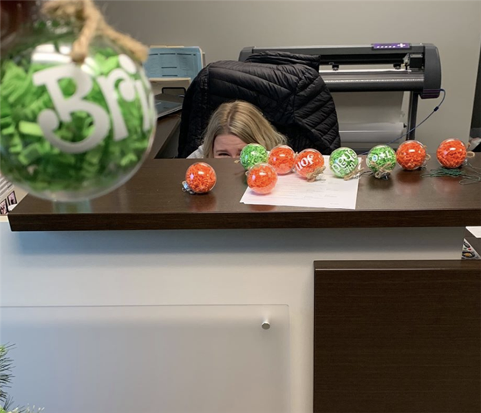 a woman hiding behind a desk with ornaments on it